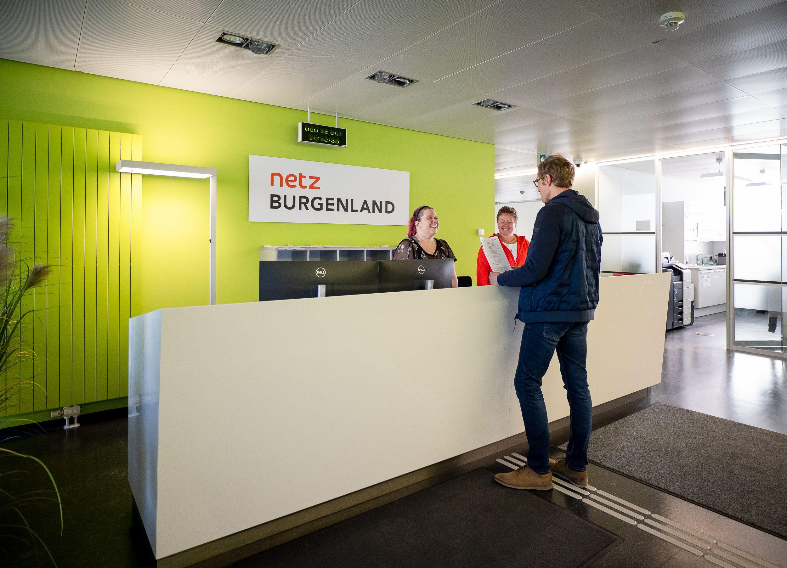 Kundenempfangsbereich von Netz Burgenland mit zwei Mitarbeitern und einem Kunden.