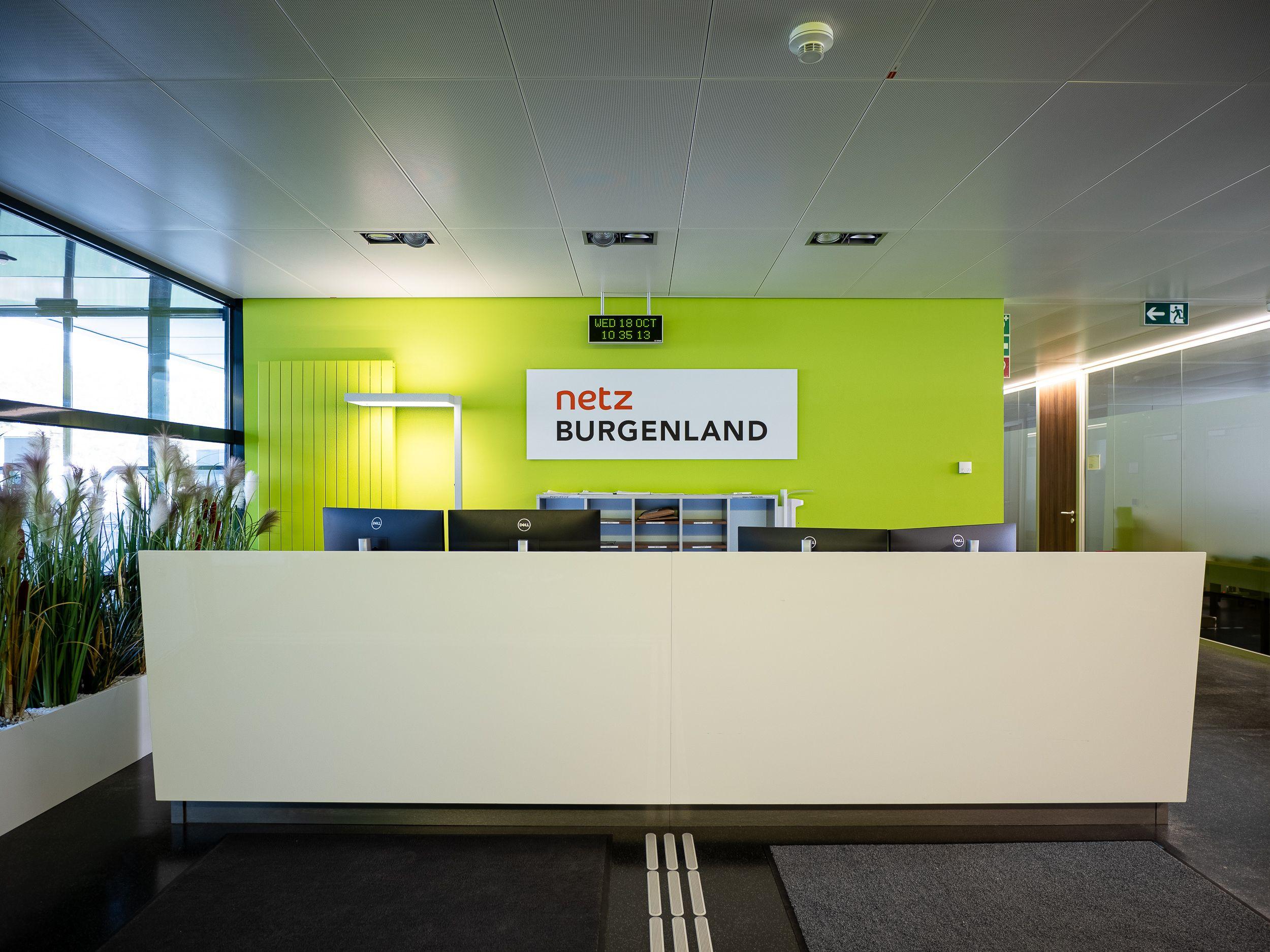 Die Rezeption im Eingangsbereich von Netz Burgenland mit markanter grüner Wand und Firmenlogo.