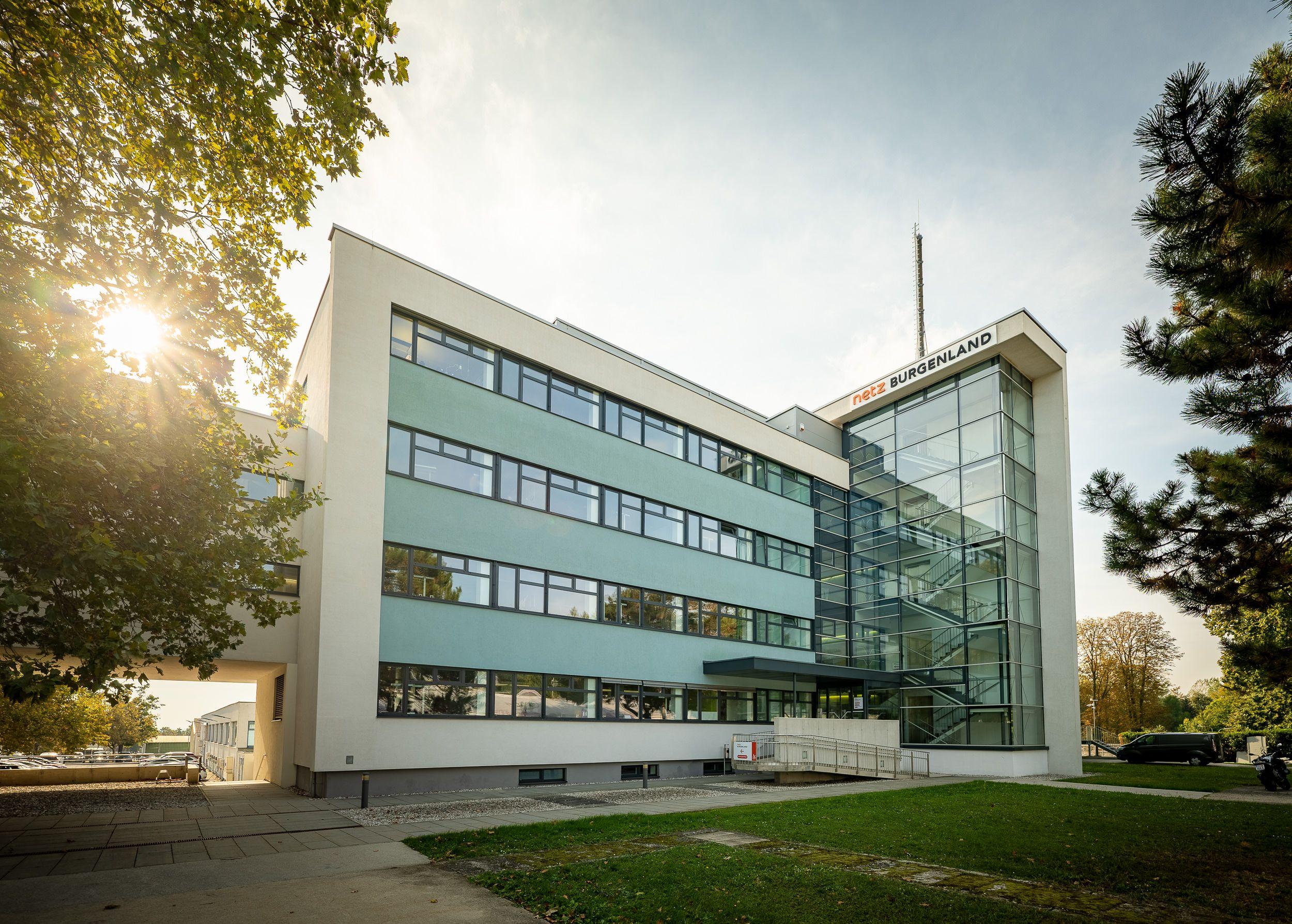 Moderne Bürogebäude von Netz Burgenland mit Glasfassade und Firmenlogo, sonniger Tag.