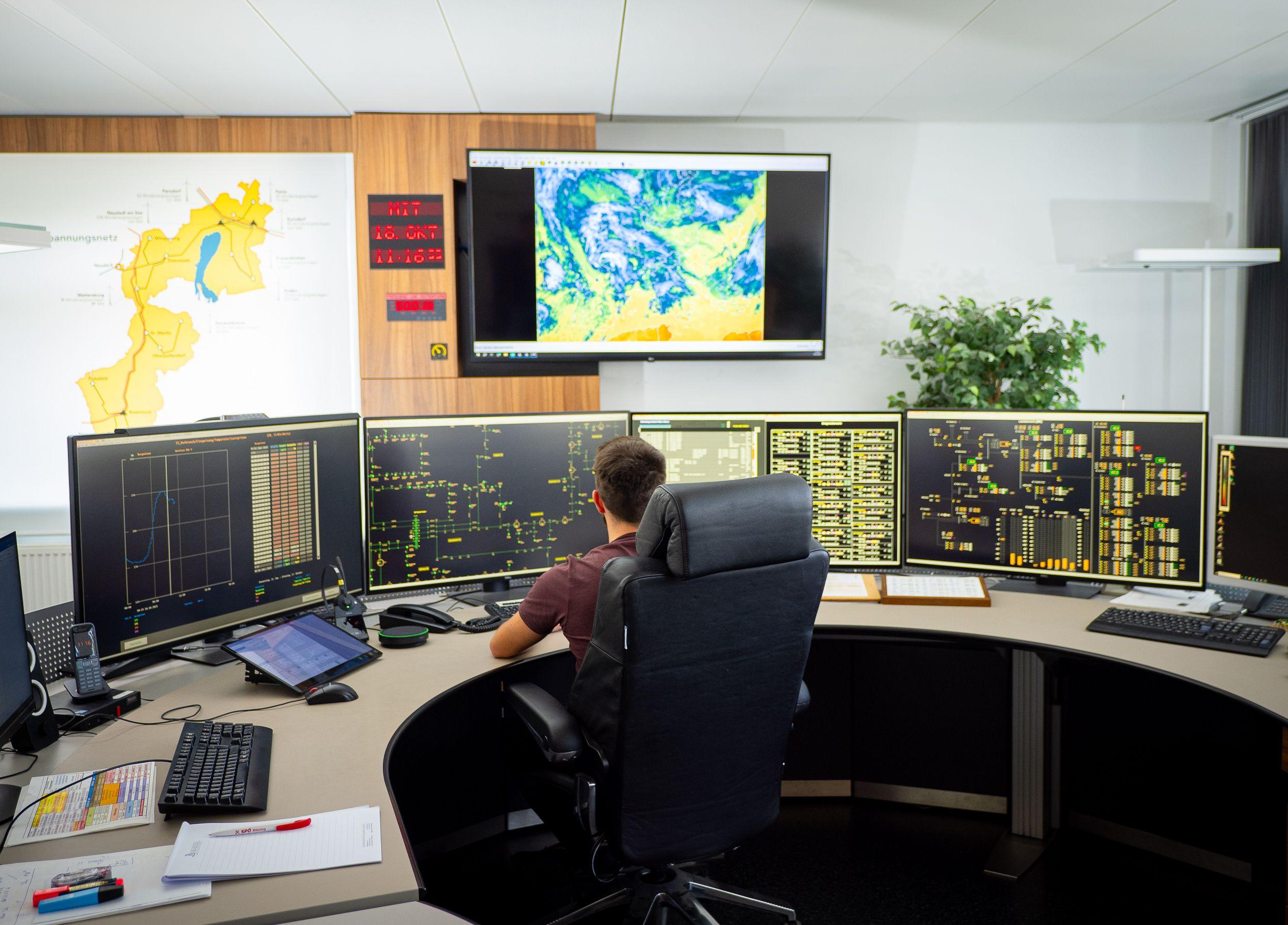 Ein Mitarbeiter überwacht Energie-Netzwerke auf mehreren Bildschirmen in einer Kontrollraum-Umgebung.