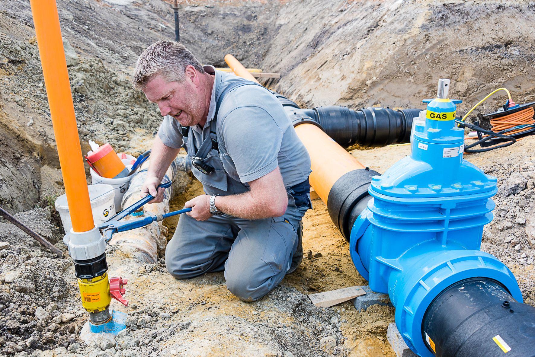Ein Netz Burgenland Techniker führt Wartungsarbeiten an Erdgasrohren in einer Baugrube durch.