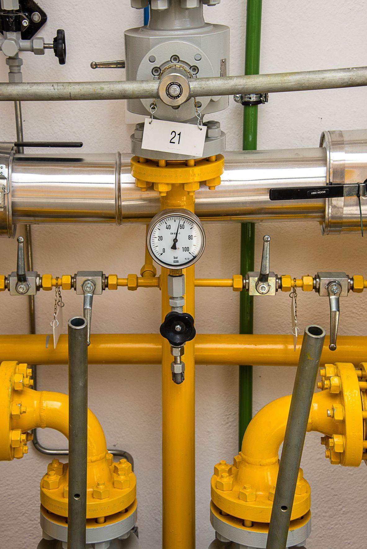 Gelbe Gasleitung mit einem Messgerät. Auf dem Messgerät sind die Zahlen 21, 40, 100 und 20 zu sehen